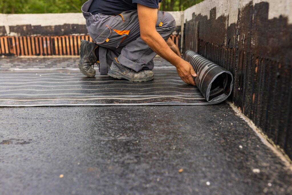 Worker laying the vapor barrier for the roof, bituminous membrane to be welded with flame